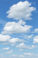 Blue cloudy sky with many beautiful white fluffy cumulus clouds in sunlight background texture