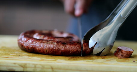 Slicing sausage with knife closeup cutting food