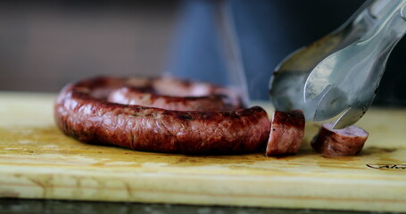 Slicing sausage with knife closeup cutting food