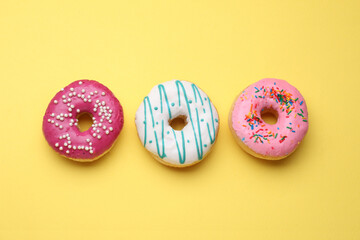 Tasty glazed donuts on yellow background, flat lay