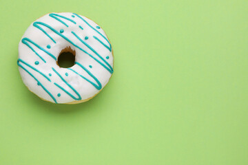 Tasty glazed donut on green background, top view. Space for text