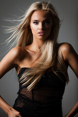 hairstyle, haircare and fashion concept - natural beautiful blond woman portrait with flying hair on grey background