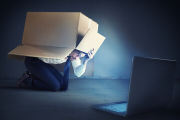 Afraid businessman hidden inside a cardboard businessman looks his laptop.   Bullying on the web concept © Designpics