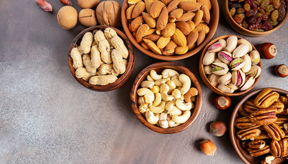 Assortment of nuts in wooden bowls. Cashew, hazelnuts, walnuts, pistachio, pecans, pine nuts, peanut, raisins. Food mix background, top view, copy space, banner.
