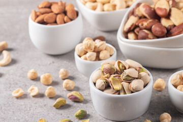Fototapeta na wymiar Large assortment of nuts in different bowls on stone table.
