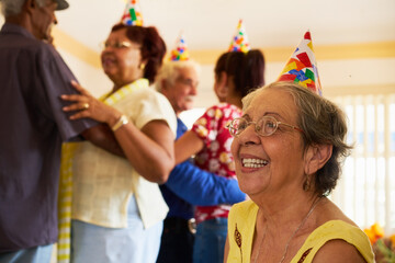 Group of old friends and family celebrating senior birthday party in retirement home. Patient woman smiling in hospice.