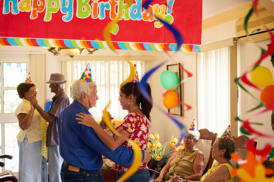 Group of old friends and family celebrating senior man birthday in retirement home. Happy elderly people having fun during party in hospice.