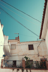 A fragment of an old residential building with a long balcony on one of the narrow streets of Spain, Andalusia