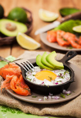 Fried egg, avocado and smoked salmon in frying pan served for breakfast