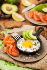 Fried egg, avocado and smoked salmon in frying pan served for breakfast