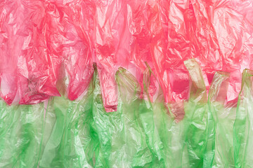 Plastic bags texture, top view crumpled plastic bag crumpled, pink and green colored textured background. Surface from Disposable polythene packet. Reusable materials, packaging waste