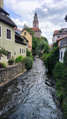 Fototapeta na wymiar Cesky Krumlov in Czech Republic. Waterway passing through a small medieval village with a castle tower in the background.