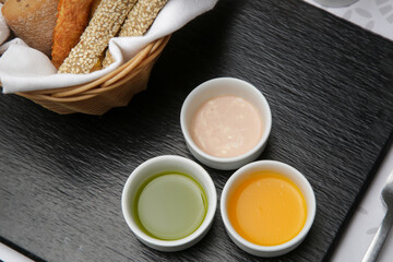 Different sauces and dips in bowls served with breadsticks on the restaurant table