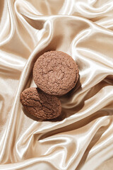 Brown american cookies on beige silk fabric background. Minimal style. Bakery and pastry concept. Top view