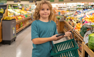 Kids with shopping basket. Shopping with kids. Kid buying fruit in supermarket. Little boy buy fresh vegetables in grocery store. Kid choosing vegetables. Healthy food.