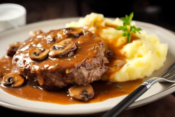 Delicious home cooked Salisbury steak with thick luscious brown mushroom gravy served with mashed potatoes on a plate. Traditional American cuisine dish specialty for family dinner holiday celebration © olindana