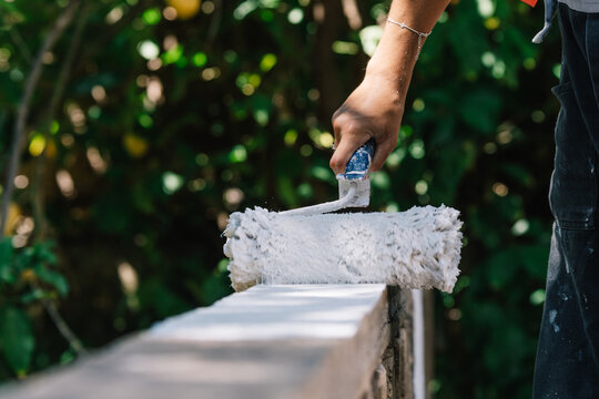 Anonymous woman painting fence with roller