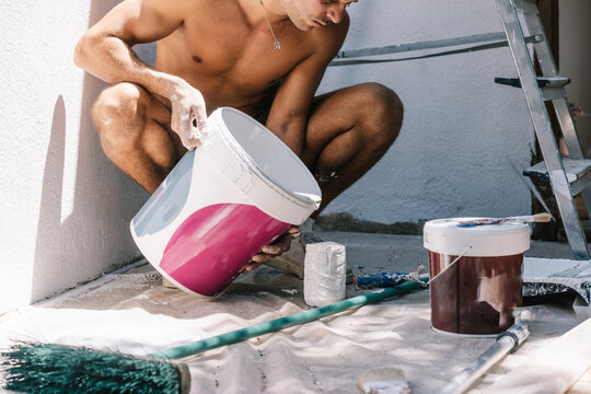 Crop man preparing paint for renovation process