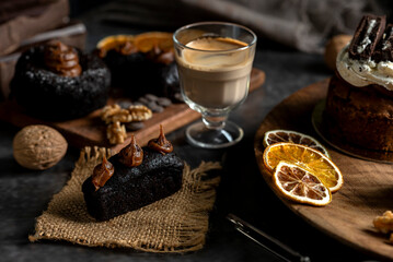cakes puddings and chocolate muffins with blueberries and cream cherries and slices of dried citrus on highly decorated wooden plate.