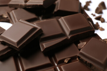 Pieces of delicious dark chocolate bar on white background, closeup