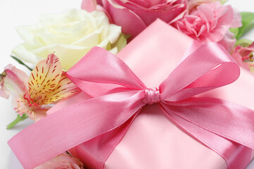 Gift box and beautiful flowers, closeup view
