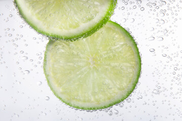 Fototapeta na wymiar Juicy lime slices in soda water, closeup
