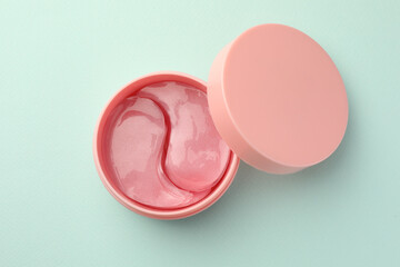 Jar of under eye patches on turquoise background, top view. Cosmetic product