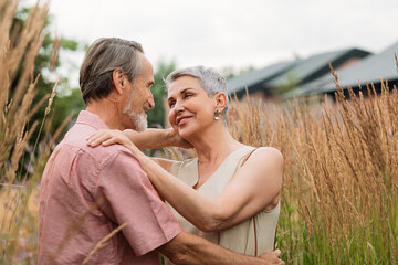 Two senior people standing together in the field and looking at each other