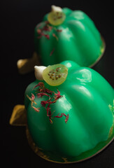 Green gooseberry mousse modern desserts with mirror glaze topped with meringue kisses and berries on black background close up