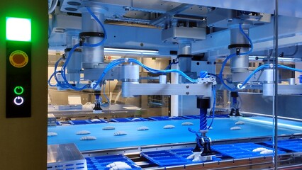 Rapid robotic production of croissants in factory. Robotic production speeds up the packaging of croissants from conveyor belt. Factory of the future is a robotic production of products at all stages.
