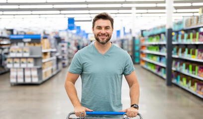 Handsome man hold shopping cart. Man holds shopping trolley. Store, shopping, sales and discounts....