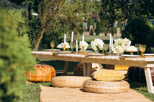 An outdoor party table arranged with exquisite flower arrangements, featuring a stunning combination of pastel gold and white decor.
