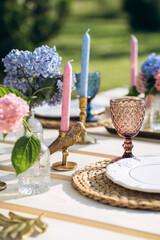 Close-up outdoor party table set up in blue and pink with gorgeous flower arrangements. Gender party decoration.