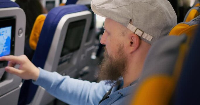 Inspired airplane passenger looks at travel map on Airplane seat screen. Cinematic video: inspired man flies to new country. Concept inspired traveler leaves his country and fly to meet new adventures