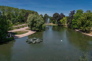 Fototapeta premium Strasbourg, France - 06 26 2023: Orangerie Park: View of the lake in the park with a jet of water and boats stationed in a star pattern.