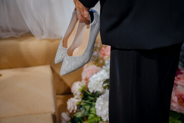 The groom holds the shoes for the bride.
