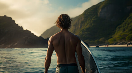 Young surfer at the beach looks out over the ocean and tropical mountains