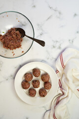 Italian (or american) meatballs spaghetti in the making and final shot. White marble background. Basil leaves on the top of the plates, with 3 meatbals on the top of the spaghetti.
