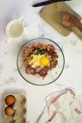 Italian (or american) meatballs spaghetti in the making and final shot. White marble background. Basil leaves on the top of the plates, with 3 meatbals on the top of the spaghetti.
