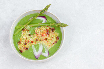 Vegetarian green soup puree with asparagus and onion in plate  top view with copy space