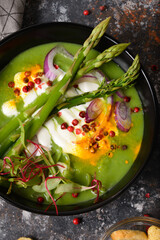 Vegetable green soup puree with asparagus, onion chard microgreens and cheese closeup