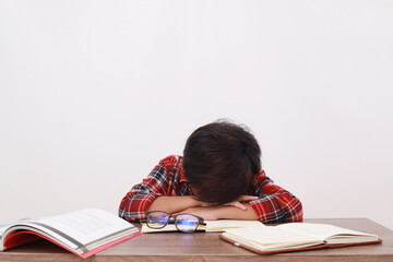 Tired asian student sleeping on the desk while studying. Isolated on white background