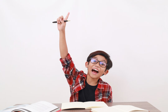 Excited asian student raising his hand while studying. Isolated on white background