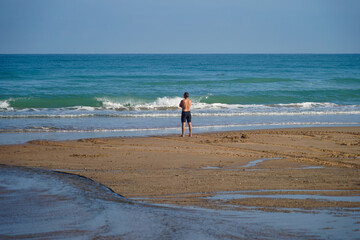 Fototapeta na wymiar Un homme qui regarde les vagues de l'océan