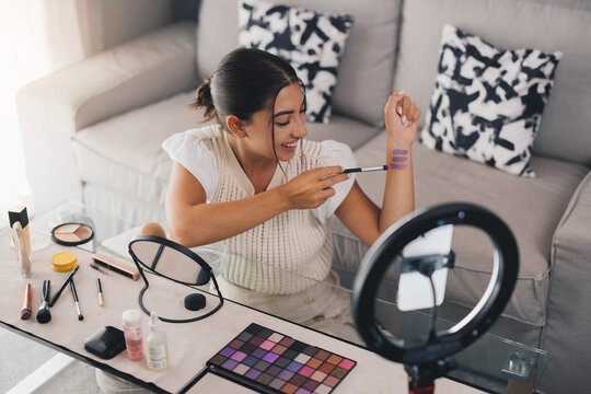 Smiling vlogger showing makeup while recording a video. female influencer.