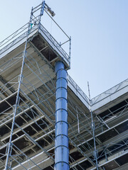 Fototapeta premium Blue plastic construction debris pipe and scaffolding at building renovation construction site