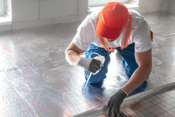 Work on underfloor heating. Sticking foil of a underfloor heating insulation. Two-in-one: EPS...
