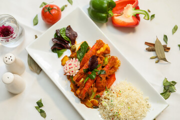 Cooked shrimps served on a party table with rice, vegetables, peppers, tomatoes, and an onion