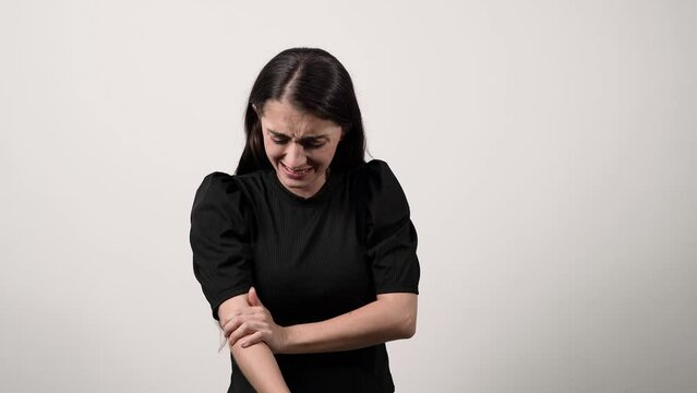 Woman in a black shirt with strong elbow pain, on a white background