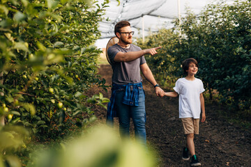 A man is walking trough he orchard with his son.